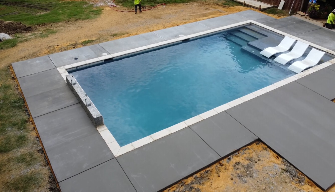 Custom concrete pool deck installation surrounding residential pool